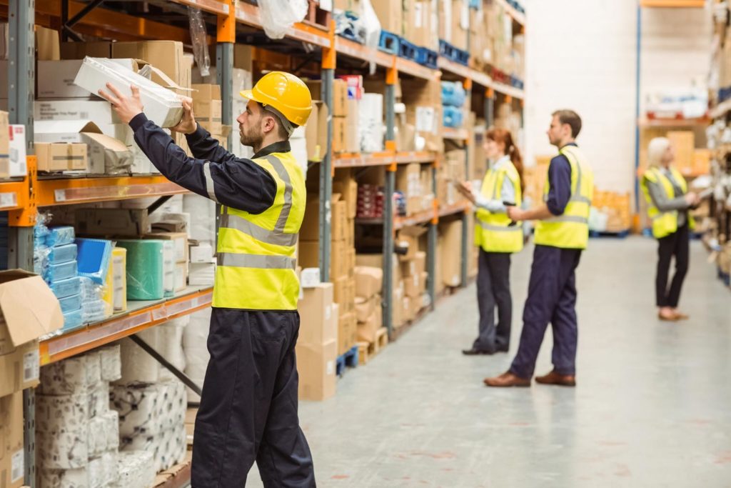 Co-packer company warehouse with workers putting items on shelves